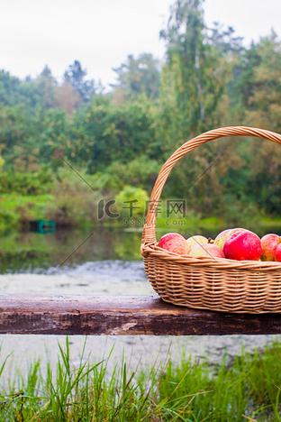 湖邊長(zhǎng)凳上放著紅黃蘋(píng)果的大草籃特寫(xiě)